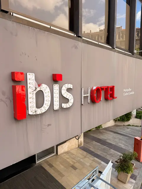 Enseigne d'hôtel abîmée à Montpellier avant intervention : lettres décollées et LED à nu