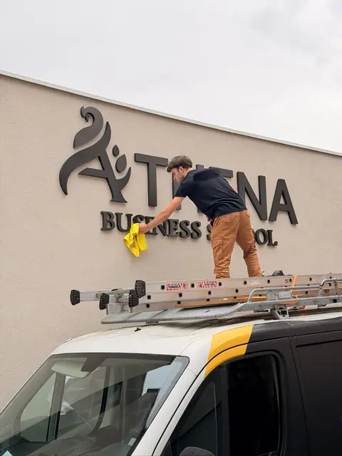 Nettoyage de lettres en relief noires sur une façade d'école